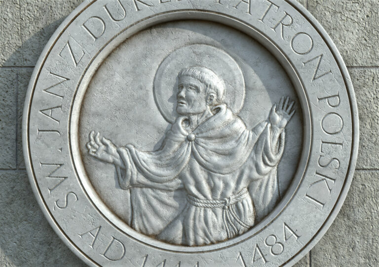 A silver medallion on a stone wall depicting a portrait of a religious figure